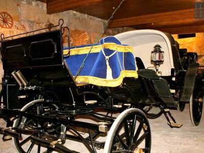La carrozza reale con un manto di velluto blu e dorato che avvolge il sedile del cocchiere